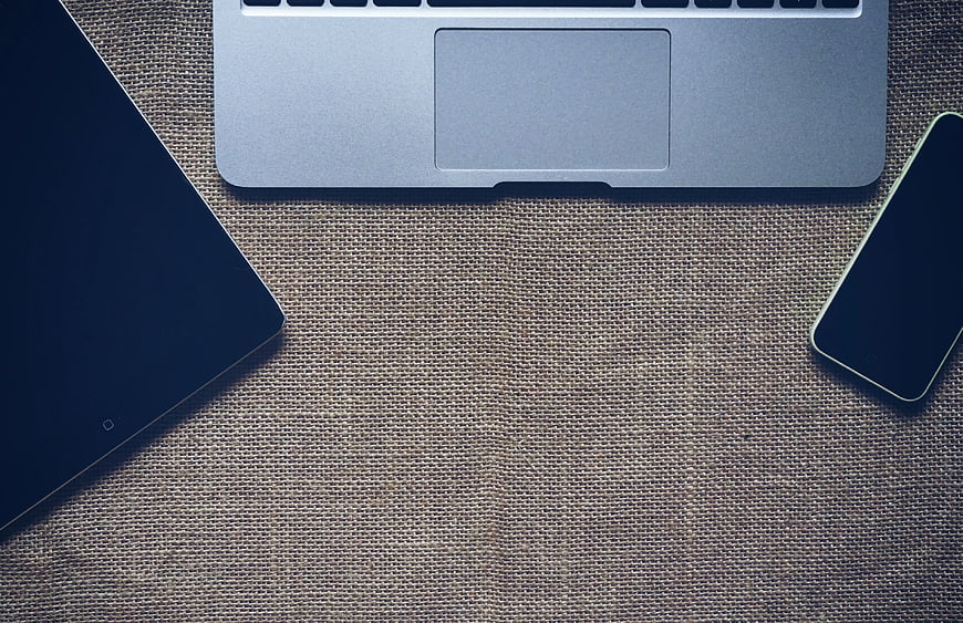 Flat lay of laptop, tablet, and smartphone on textured fabric