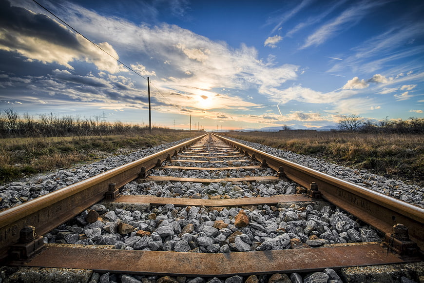 Rusty railway tracks stretching into the sunset horizon