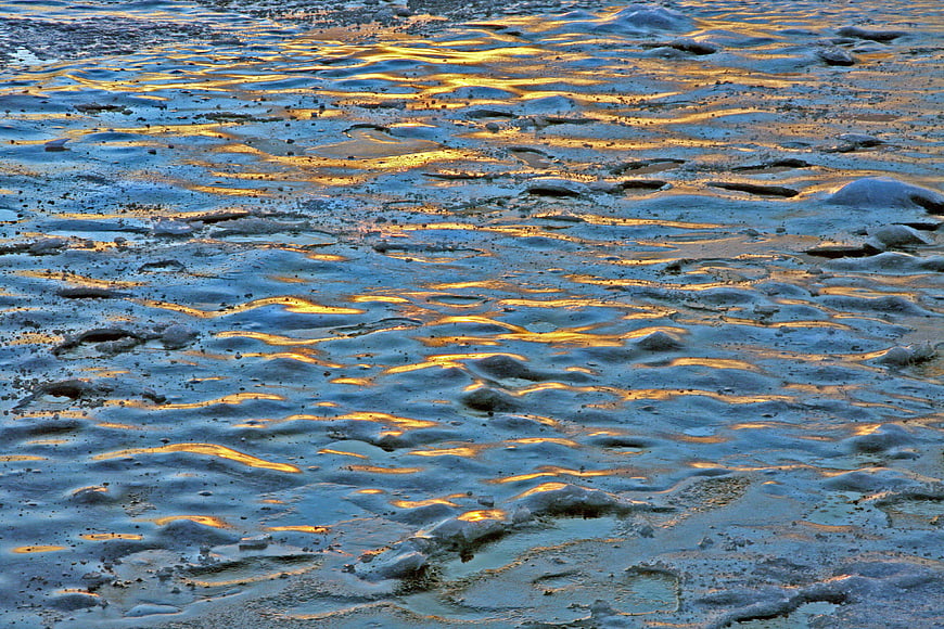 Golden sunset reflection on frozen icy winter landscape