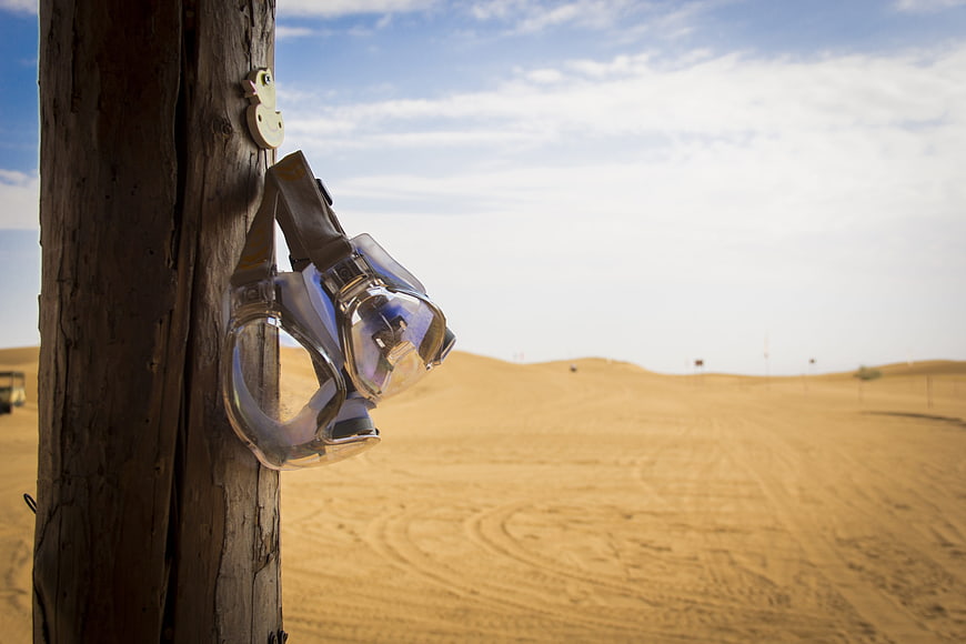 Safety goggles hanging on wooden post in desert landscape