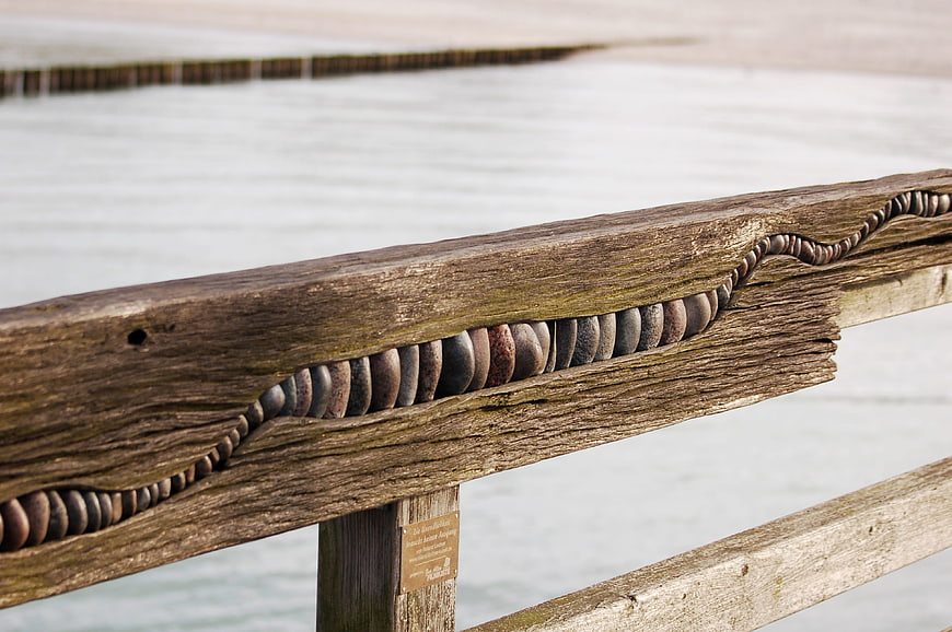 Close-up of weathered wooden railing with carved stone inlay