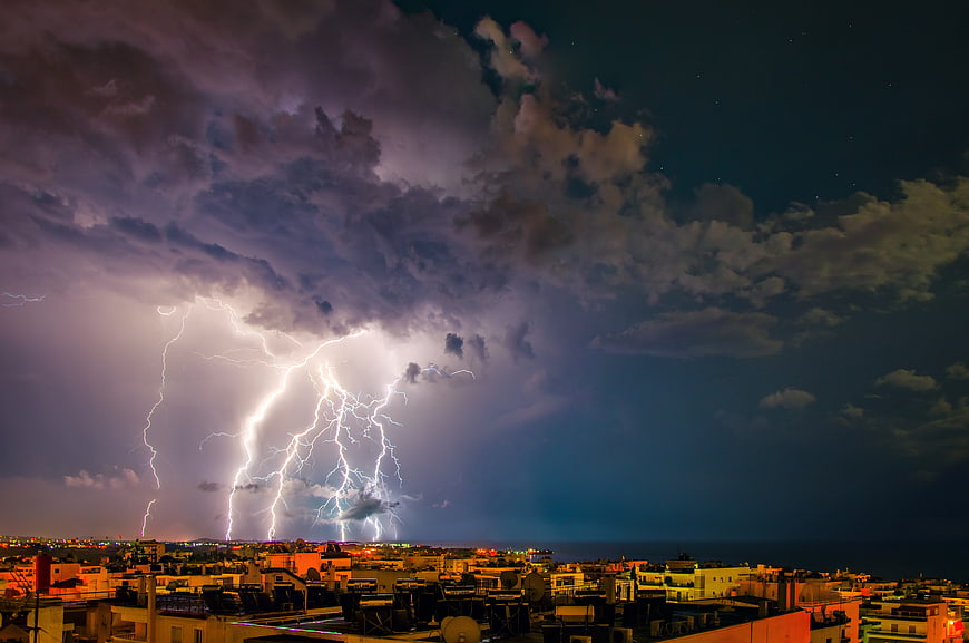 Dramatic Lightning Storm Over City Rooftops at Night