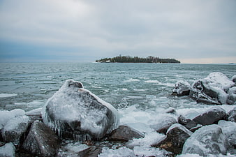 Frozen Lake Shore with Ice-Covered Rocks and Distant Island