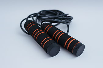 Black and orange skipping rope with foam handles on white background