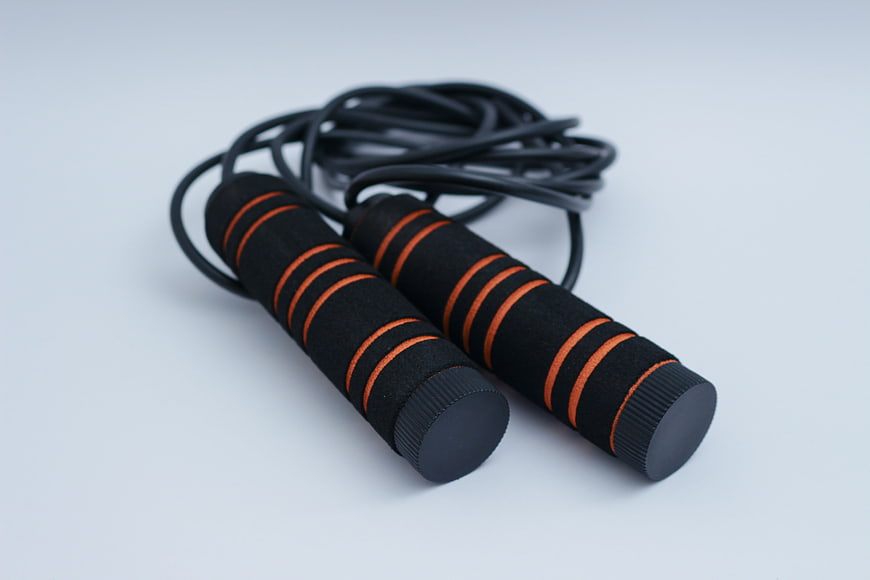Black and orange skipping rope with foam handles on white background