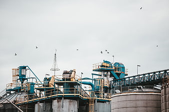 Industrial factory complex with blue machinery and flying birds