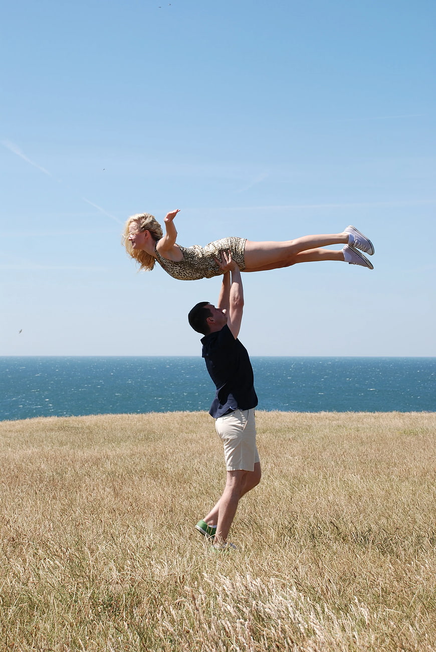 Happy Couple Playing in Grassy Field by the Sea
