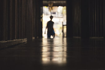 Silhouette of person walking through dark wooden corridor