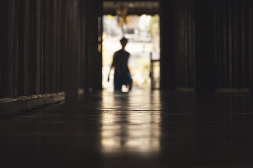 Silhouette of person walking through dark wooden corridor