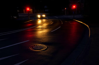 Wet City Street at Night with Red Traffic Lights and Headlights