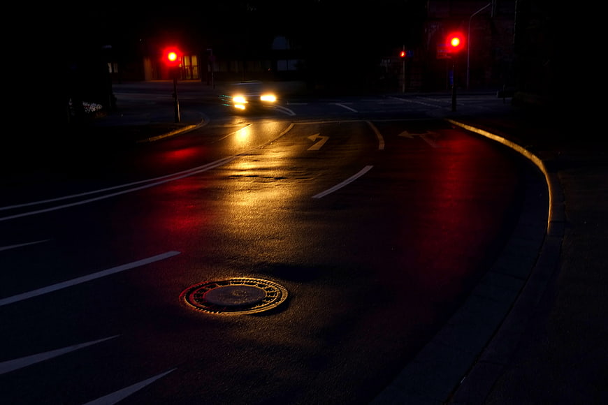 Wet City Street at Night with Red Traffic Lights and Headlights