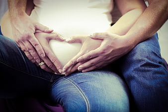 Pregnant Couple Forming Heart Shape with Hands on Belly