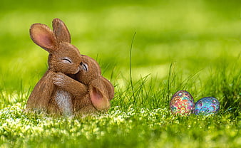 Cute Easter Bunny Figurines Hugging with Decorated Eggs in Grass