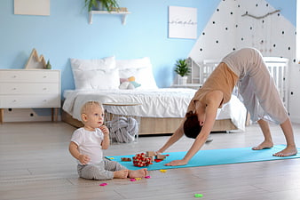 Mother doing yoga while baby plays in bedroom
