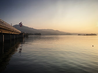 Serene Lake Landscape with Bridge and Mountains at Sunset