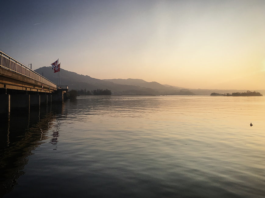 Serene Lake Landscape with Bridge and Mountains at Sunset