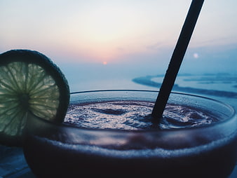 Close-up of a cold cocktail with lime garnish at sunset