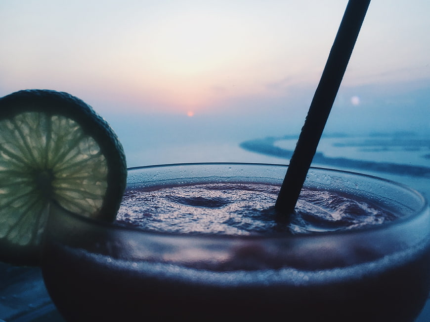 Close-up of a cold cocktail with lime garnish at sunset