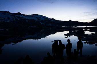 Silhouettes of Hikers by Mountain Lake at Dusk