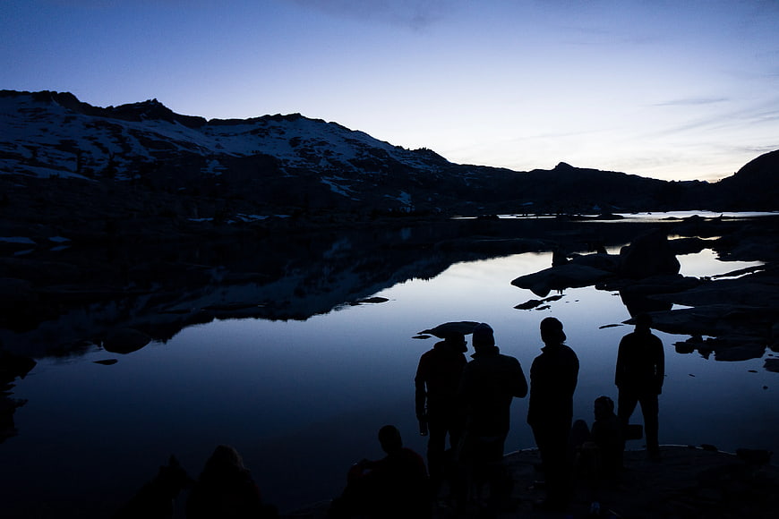 Silhouettes of Hikers by Mountain Lake at Dusk