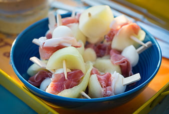 Prosciutto and melon skewers with mozzarella in blue bowl