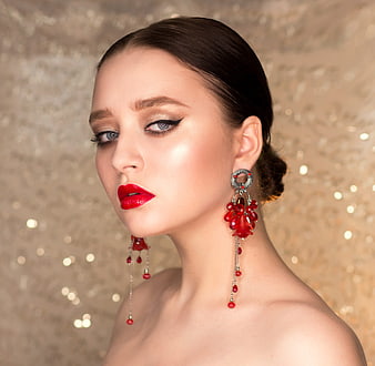 Elegant Woman Portrait with Red Jewelry and Glitter Background