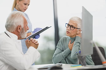 Senior doctor consulting with elderly patient and nurse in clinic
