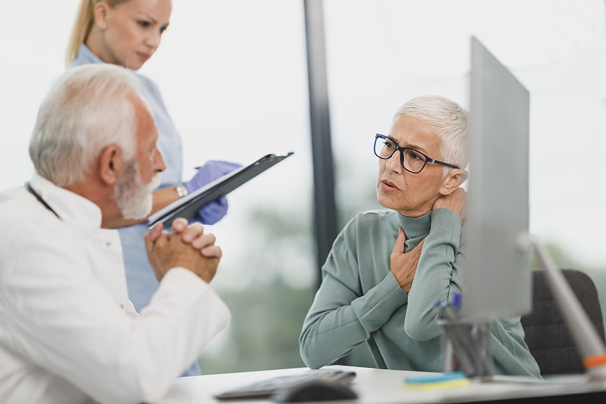 Senior doctor consulting with elderly patient and nurse in clinic