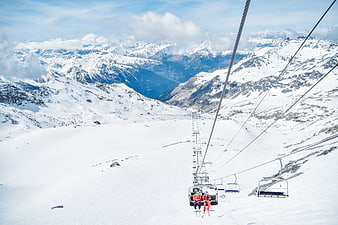 Ski lift view over snowy mountain range with skiers