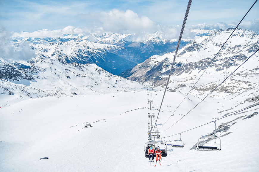 Ski lift view over snowy mountain range with skiers