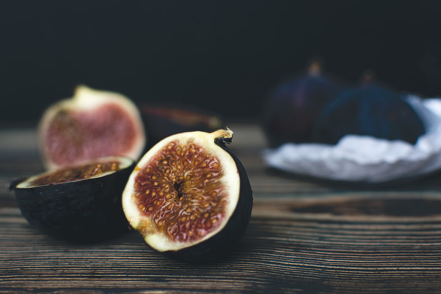 Fresh Ripe Figs Cut in Half on Dark Wood