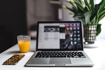 Modern Workspace with MacBook, Orange Juice, and Smartphone
