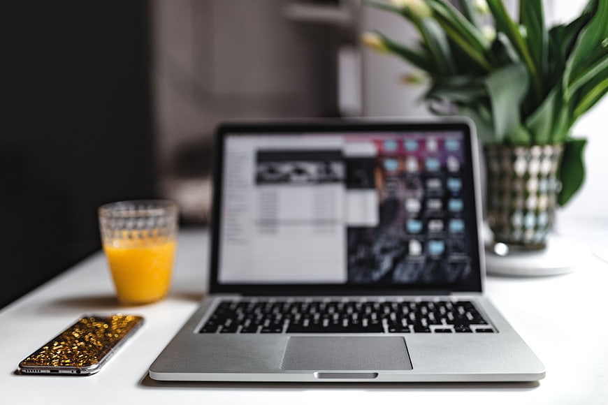 Modern Workspace with MacBook, Orange Juice, and Smartphone