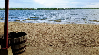 Sandy Lake Shoreline With Wooden Barrel And Red Pole
