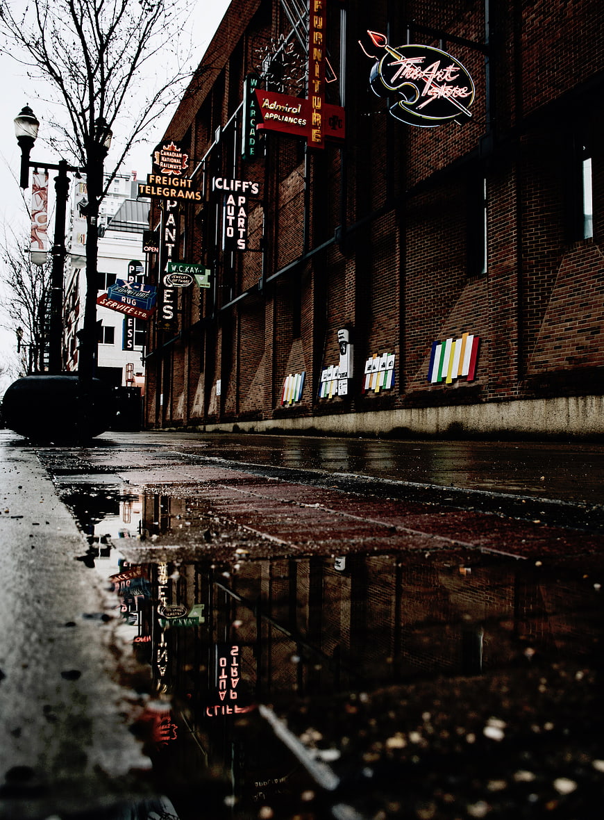 Low angle street view with neon signs reflected in puddle