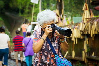 Senior woman taking photo with DSLR camera outdoors