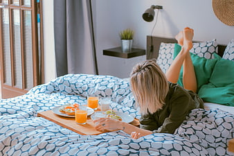 Woman enjoying breakfast in bed with orange juice
