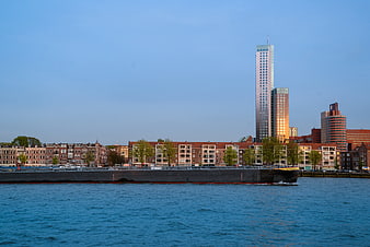 Cargo ship sailing on river with Rotterdam skyline and Maastoren