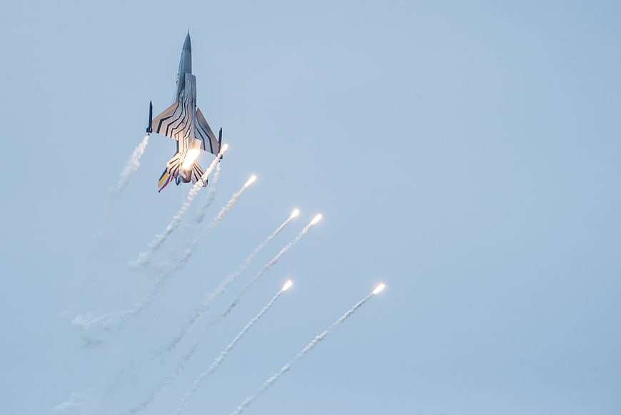 Military Jet Fighter Releasing Flares in Blue Sky