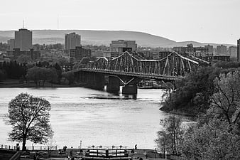 Black and White Cityscape with Steel Truss Bridge Over River