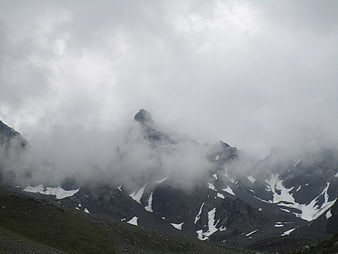 Misty mountain peaks with snow patches in the alps