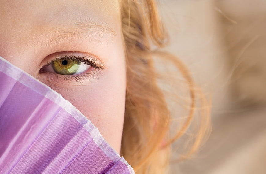 Close-up of woman's green eye with purple face mask
