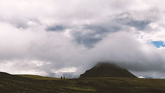 Two Hikers Walking on Green Highland Under Cloudy Sky