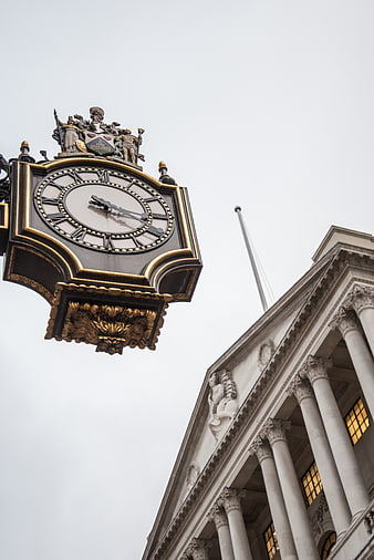 Ornate black and gold clock against classical architecture