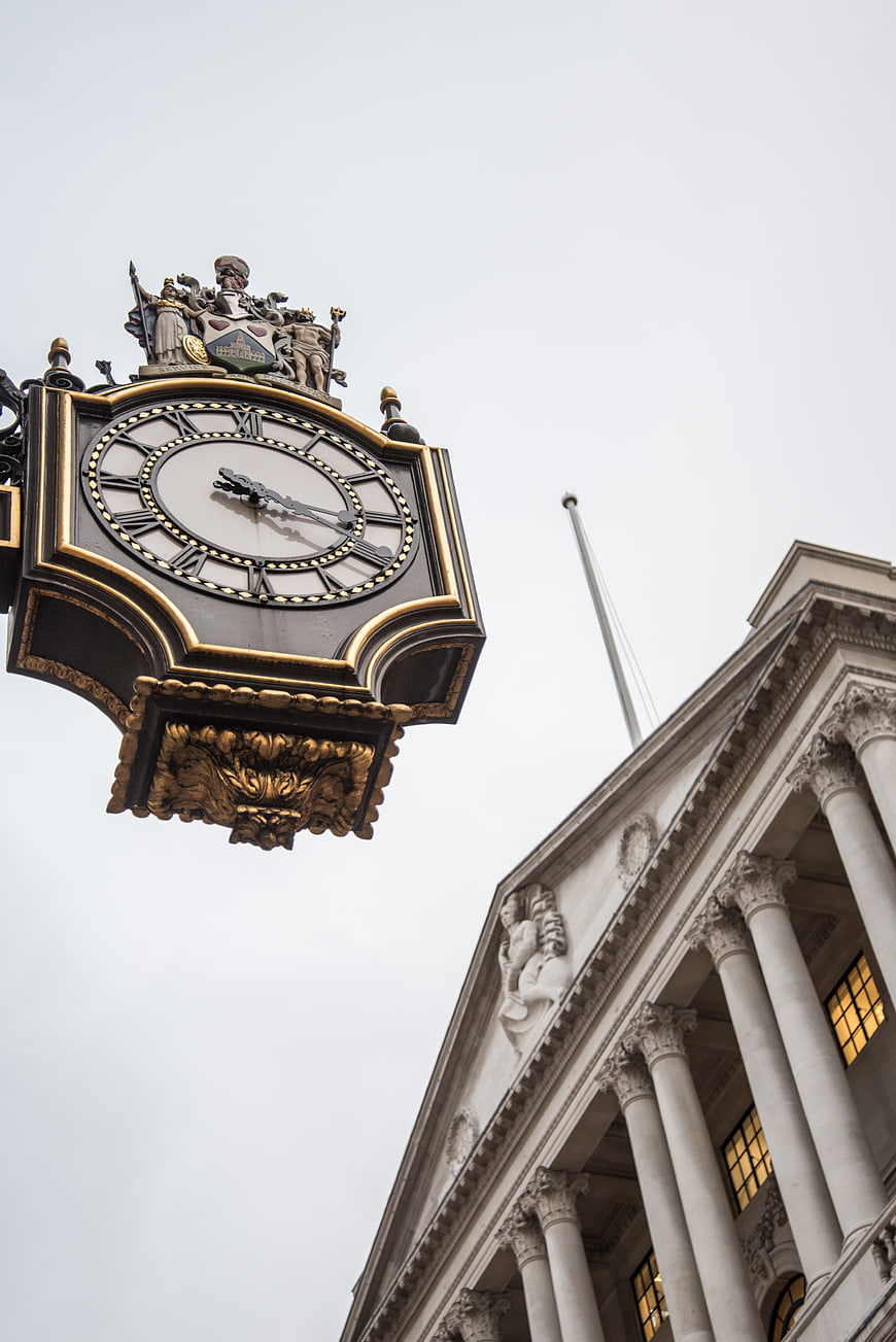 Ornate black and gold clock against classical architecture