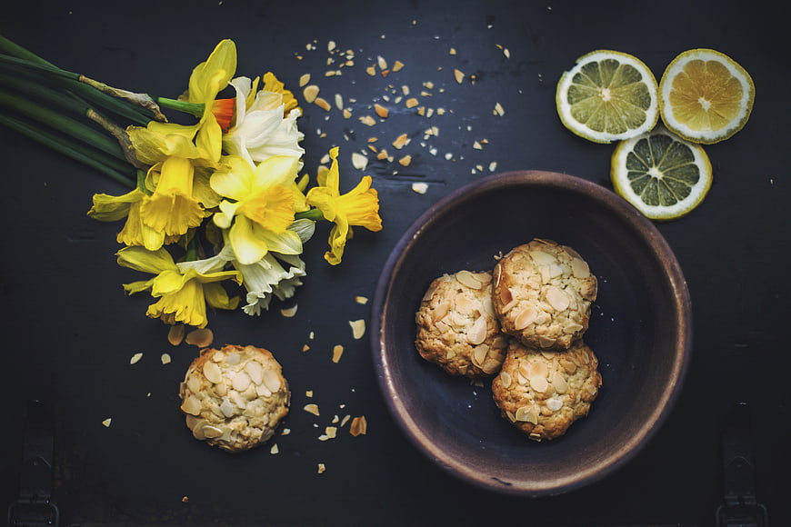 Almond cookies with daffodils and lemon slices on dark background