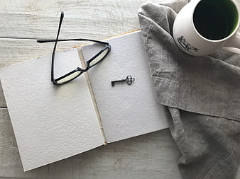 Flat lay of open book, glasses, key, and coffee mug