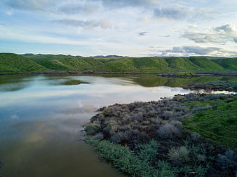 Serene river winding through green rolling hills landscape