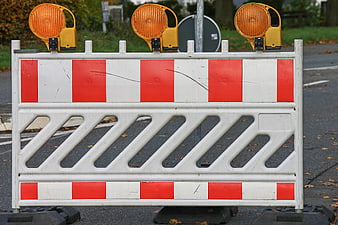 Red and white road barrier with three orange warning lights