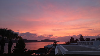 Vibrant pink and orange sunset over coastal resort with palm trees